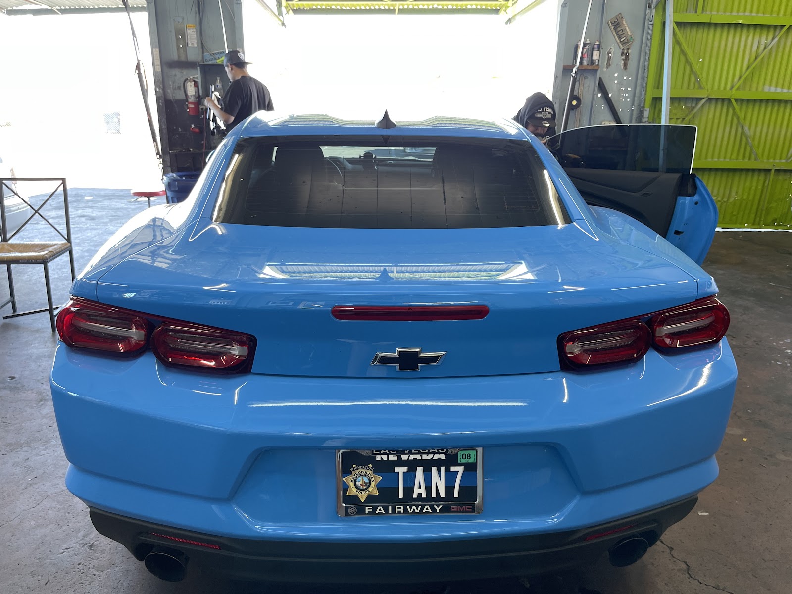 Rear view of a blue Chevrolet Camaro with tinted rear glass inside a shop bay